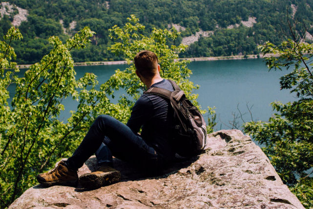 man sitting on a rock overlooking a river